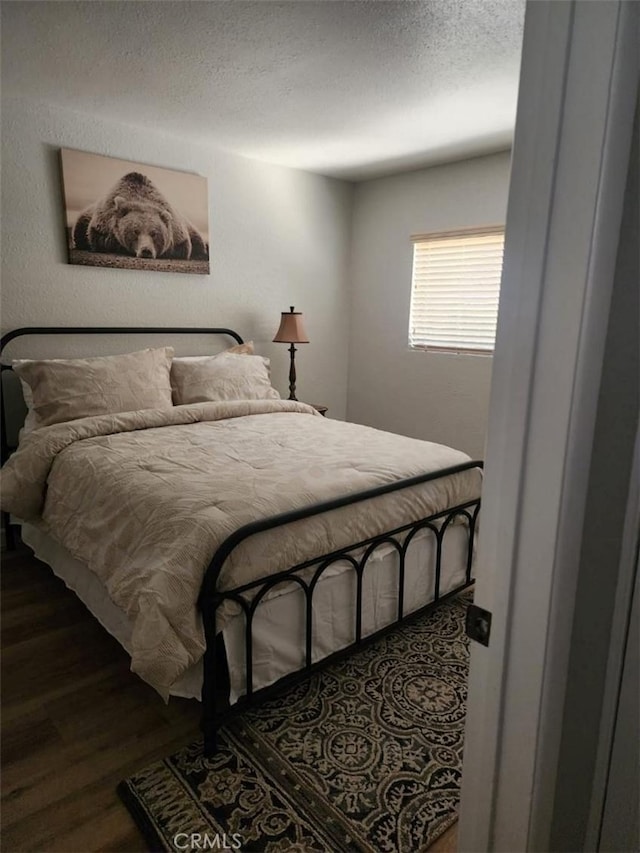 bedroom with a textured ceiling and dark hardwood / wood-style flooring