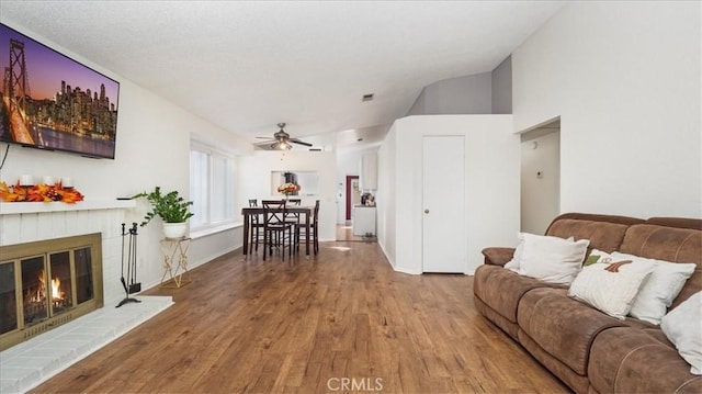 living room with hardwood / wood-style floors, ceiling fan, a fireplace, and high vaulted ceiling