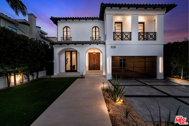 view of front facade featuring a garage, a yard, and a balcony