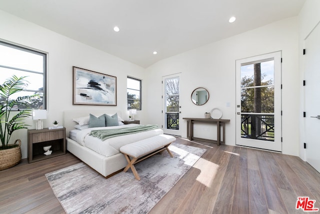 bedroom featuring access to exterior, wood-type flooring, vaulted ceiling, and multiple windows