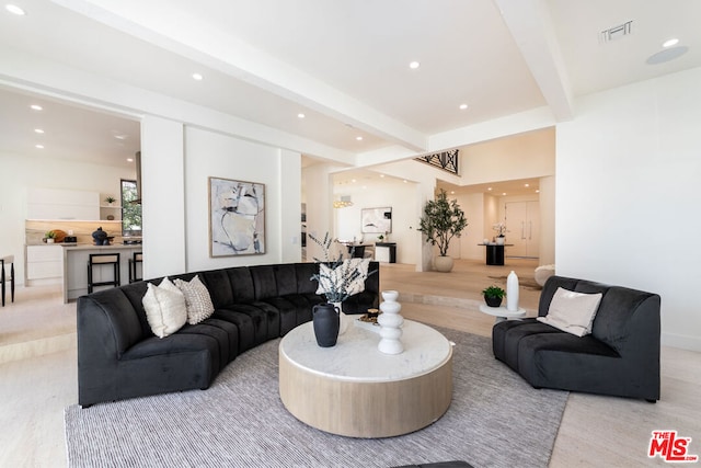 living room featuring beamed ceiling and light hardwood / wood-style floors