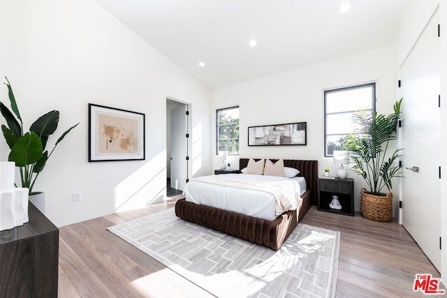 bedroom featuring hardwood / wood-style floors, vaulted ceiling, and multiple windows