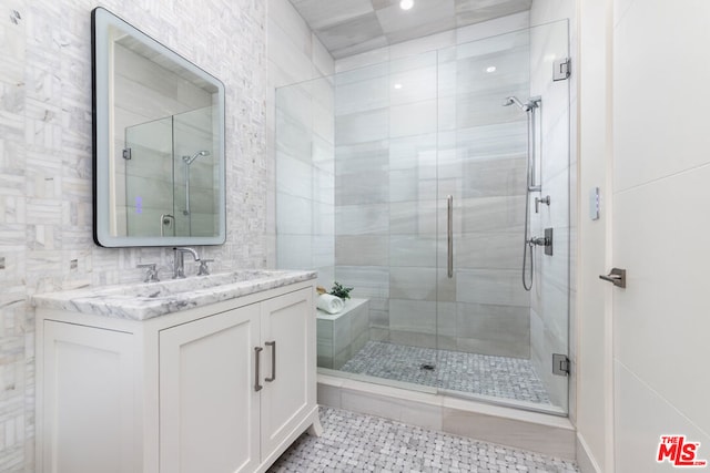 bathroom with tile patterned flooring, vanity, a shower with shower door, and tile walls