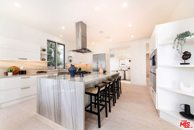 kitchen with light stone countertops, stainless steel appliances, white cabinetry, and exhaust hood