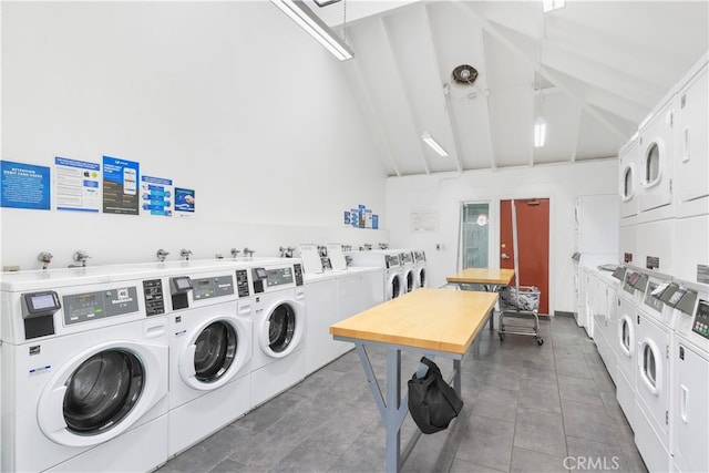 laundry area with washer and clothes dryer, stacked washer and dryer, a towering ceiling, and dark tile patterned flooring