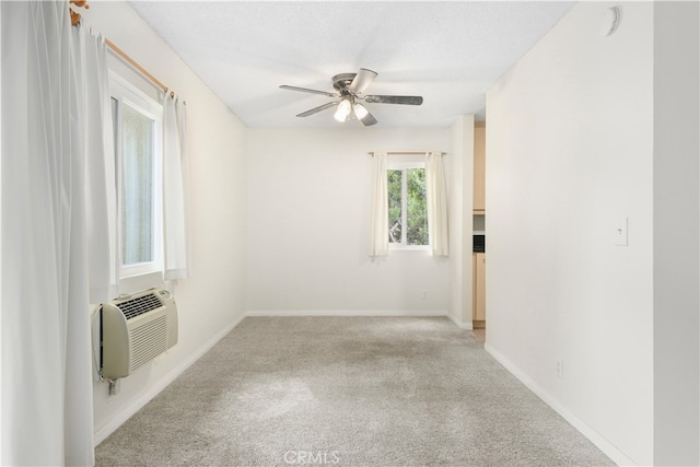 carpeted empty room featuring a wall mounted air conditioner, ceiling fan, and a textured ceiling