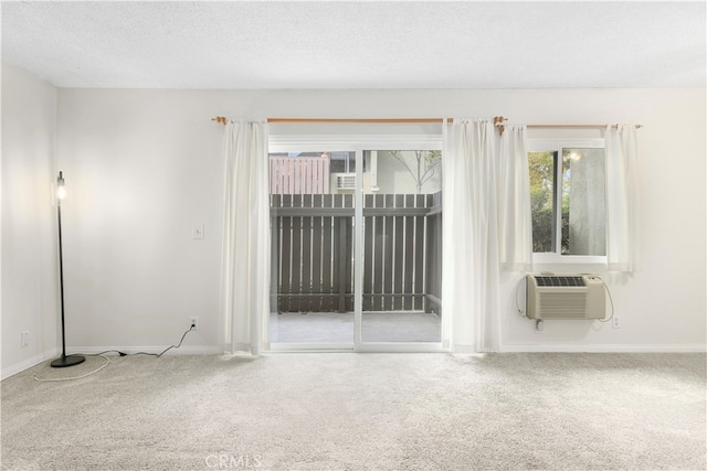 carpeted empty room featuring a textured ceiling and a wall mounted AC