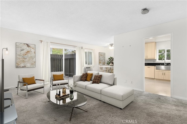 living room featuring a textured ceiling, ceiling fan, light colored carpet, and sink