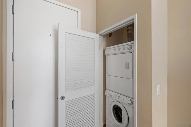 clothes washing area featuring stacked washer and clothes dryer