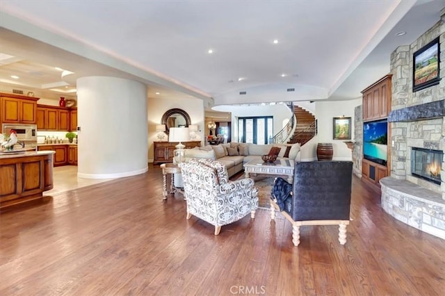 living room featuring a fireplace, wood-type flooring, and vaulted ceiling