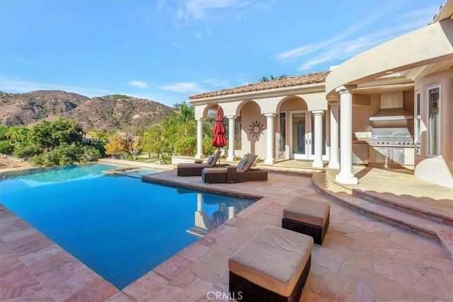 view of pool featuring grilling area, a mountain view, a patio, and an outdoor kitchen