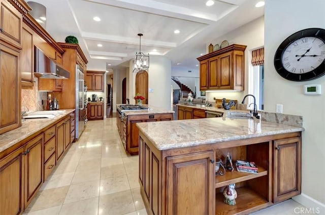 kitchen featuring sink, kitchen peninsula, pendant lighting, a kitchen island, and exhaust hood