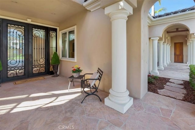 view of exterior entry with french doors and a porch