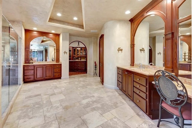 bathroom with a raised ceiling, a shower with door, and vanity