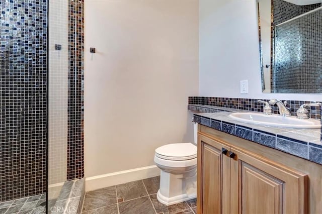 bathroom with tile patterned flooring, a tile shower, vanity, and toilet