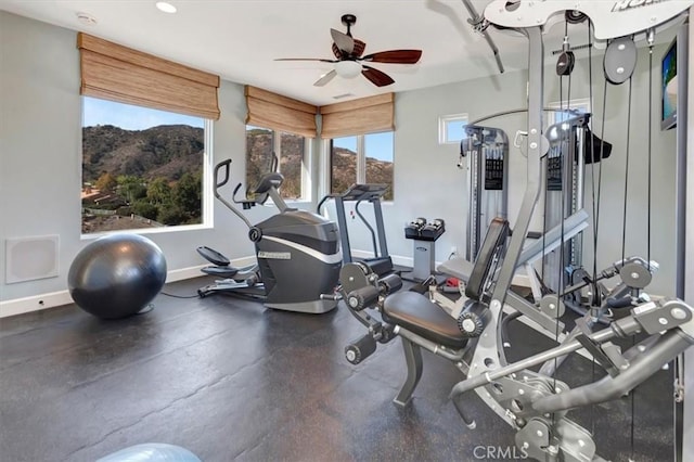 workout room with a mountain view and ceiling fan