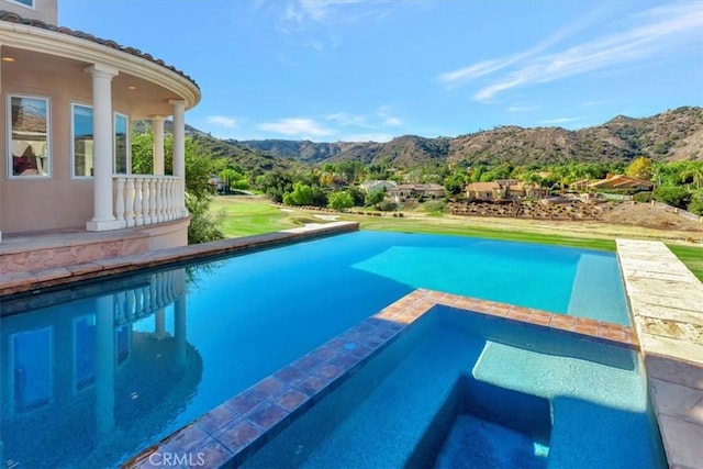 view of swimming pool featuring an in ground hot tub and a mountain view