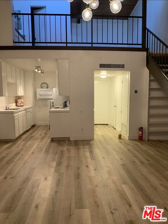 interior space featuring sink, a towering ceiling, and light wood-type flooring