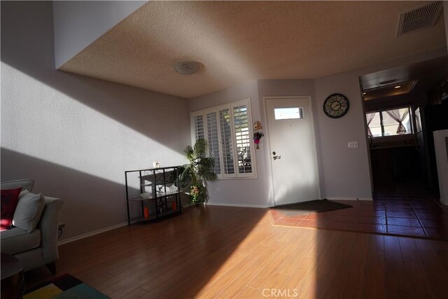 foyer entrance with wood-type flooring and a textured ceiling