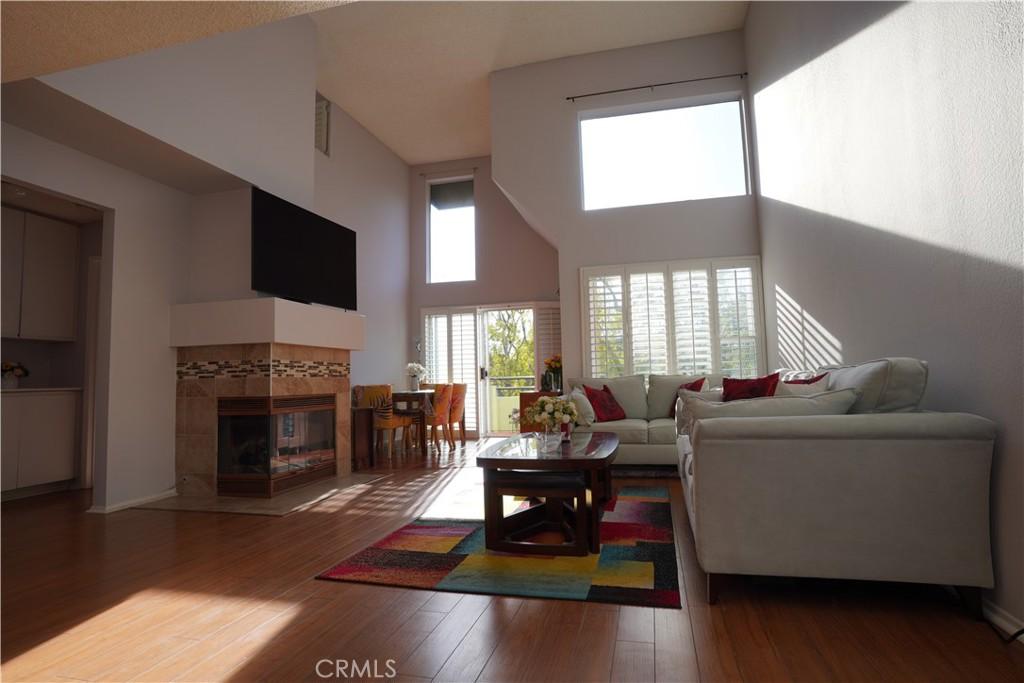 living room with a tiled fireplace, a towering ceiling, and hardwood / wood-style flooring