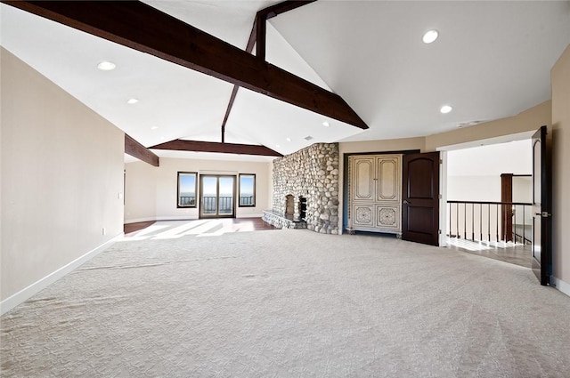 unfurnished living room featuring vaulted ceiling with beams, a fireplace, and light colored carpet