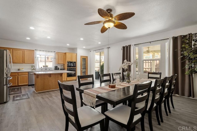 dining space featuring a textured ceiling, light hardwood / wood-style floors, and ceiling fan