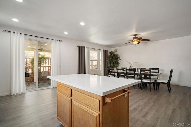 kitchen with ceiling fan, hardwood / wood-style floors, a kitchen island, and a healthy amount of sunlight