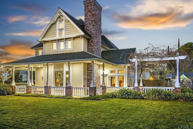 back house at dusk with a yard and a porch