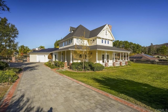 farmhouse inspired home with a front lawn, a porch, and a garage