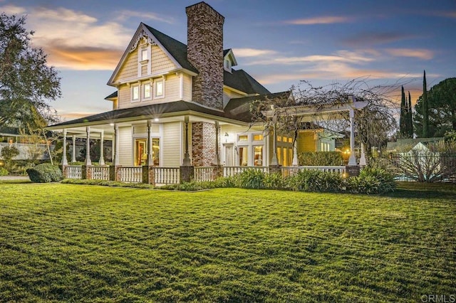 back house at dusk featuring a lawn