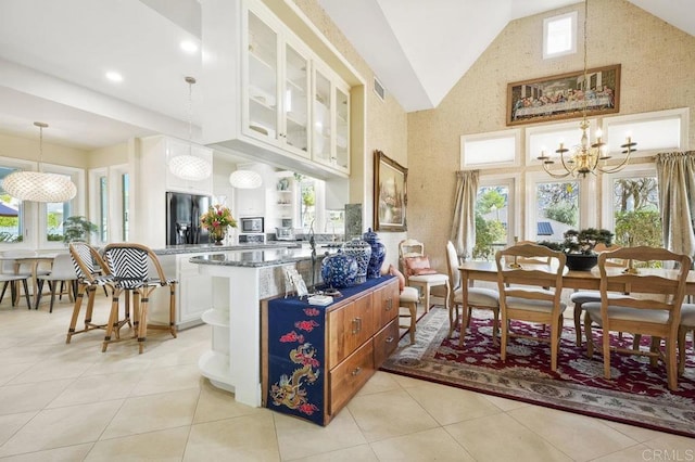 dining area featuring a chandelier, light tile patterned flooring, and vaulted ceiling