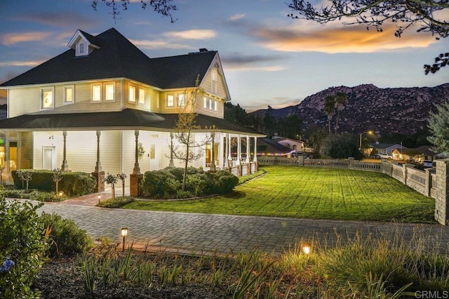 back house at dusk featuring a lawn and a mountain view