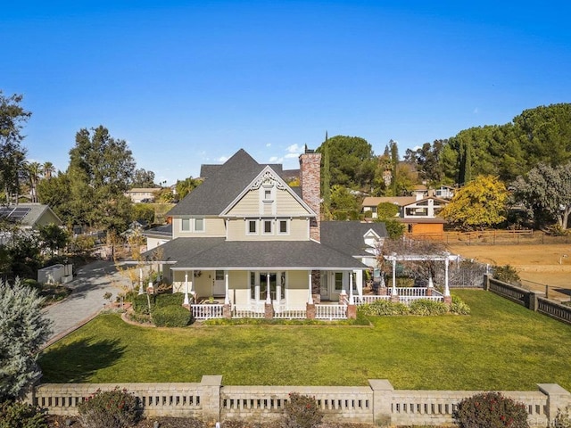 back of property with a porch, a pergola, and a yard