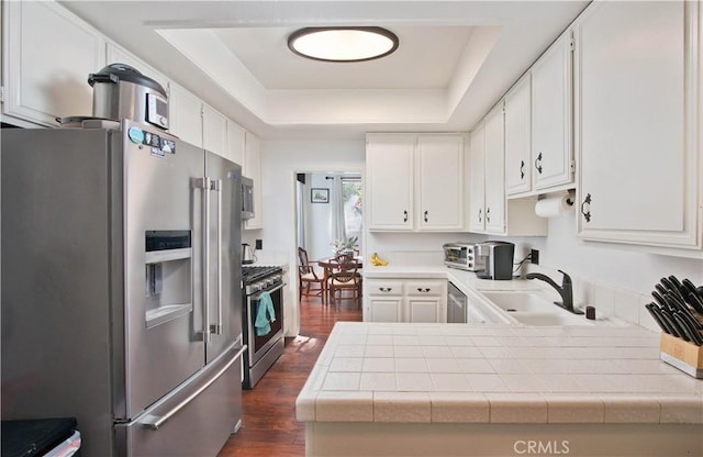 kitchen with tile countertops, dark hardwood / wood-style floors, white cabinets, and appliances with stainless steel finishes