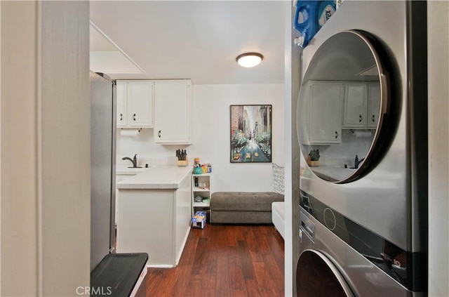 laundry area with stacked washer and dryer, dark hardwood / wood-style floors, and sink