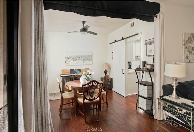 dining area with a barn door, ceiling fan, and dark wood-type flooring