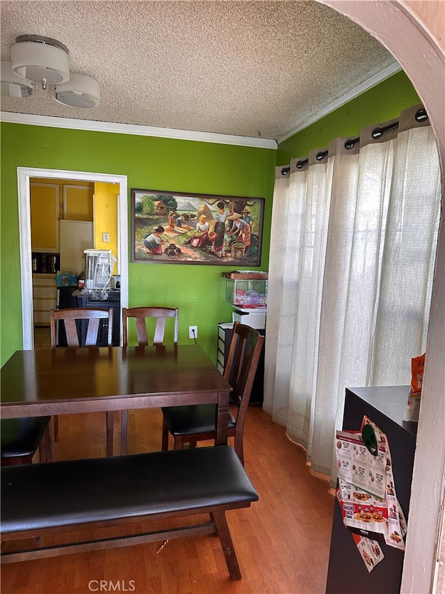 dining room with hardwood / wood-style flooring, ornamental molding, and a textured ceiling