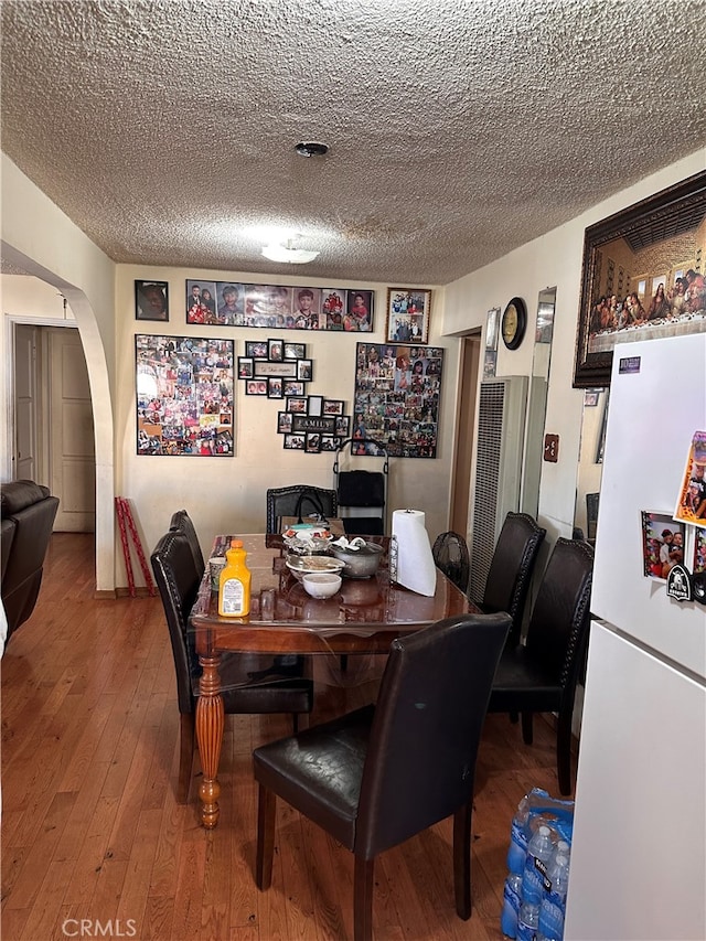 dining area with hardwood / wood-style flooring and a textured ceiling