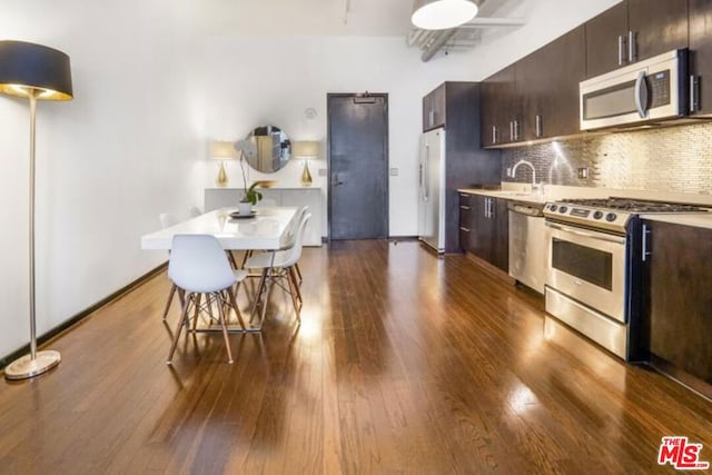 kitchen with dark hardwood / wood-style floors, a kitchen bar, dark brown cabinetry, and appliances with stainless steel finishes