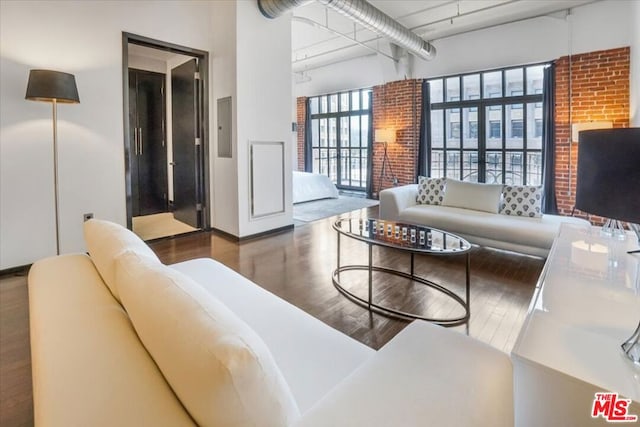 living room with wood-type flooring, a towering ceiling, and electric panel