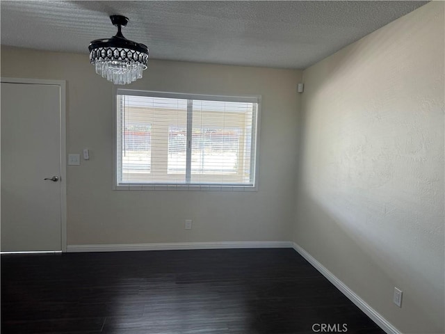 spare room with a textured ceiling and dark hardwood / wood-style floors