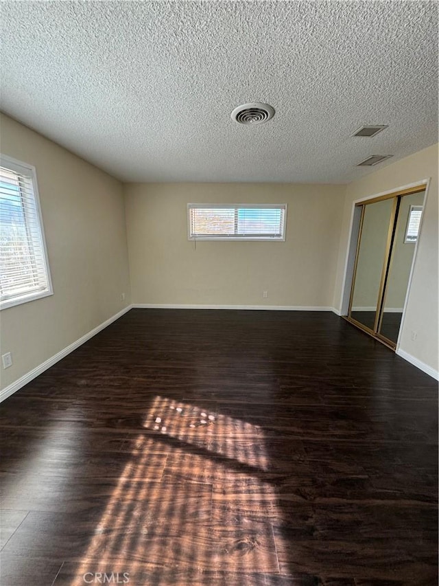 spare room featuring dark hardwood / wood-style flooring and a textured ceiling