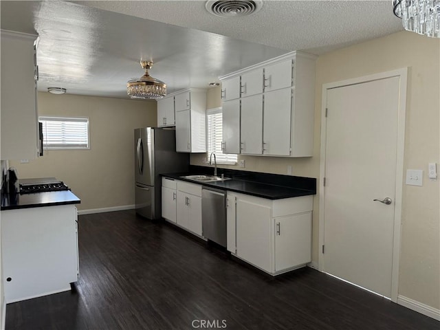 kitchen with white cabinets, appliances with stainless steel finishes, dark hardwood / wood-style floors, and sink