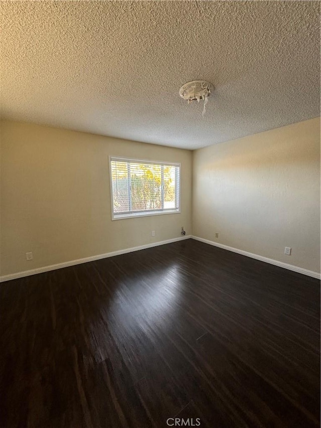 spare room featuring a textured ceiling and dark wood-type flooring