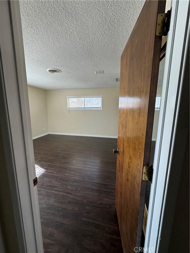 unfurnished room featuring a textured ceiling and dark hardwood / wood-style floors