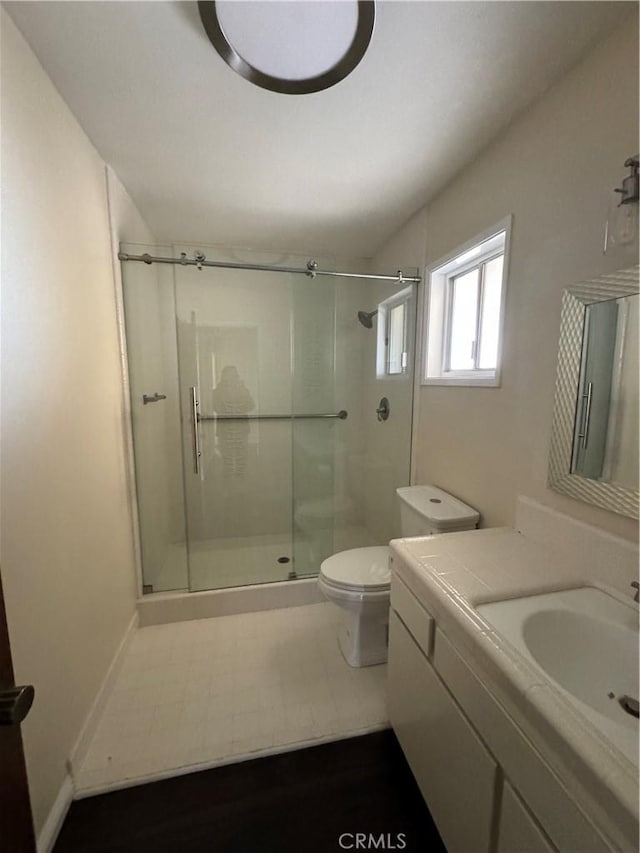 bathroom with tile patterned flooring, vanity, toilet, and walk in shower