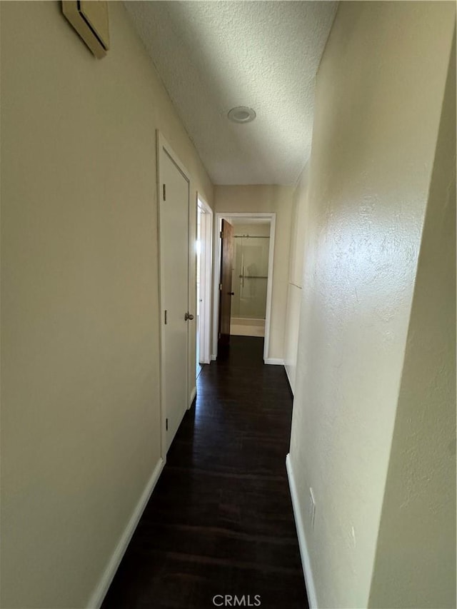 corridor featuring an AC wall unit, dark hardwood / wood-style flooring, and a textured ceiling