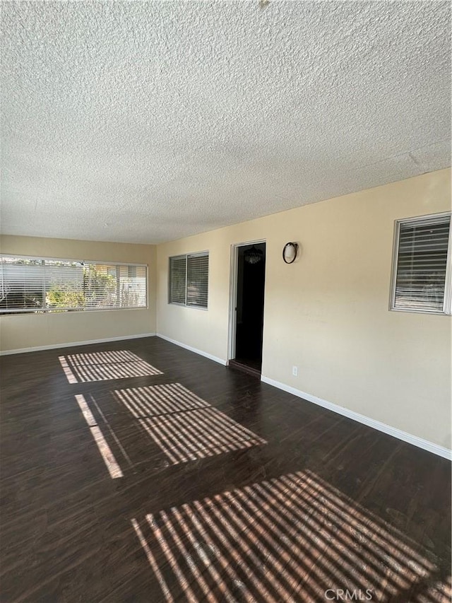 unfurnished room with a textured ceiling and dark hardwood / wood-style floors