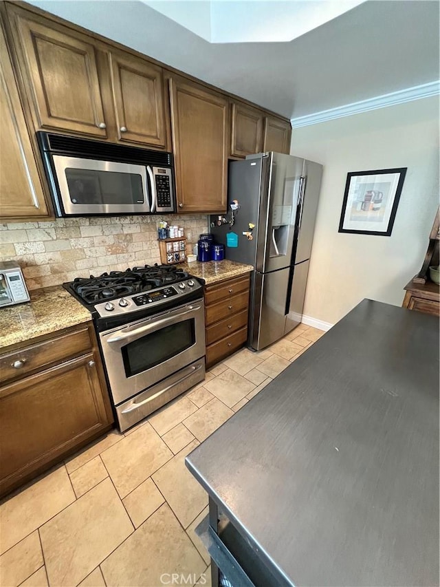 kitchen with decorative backsplash, light tile patterned floors, appliances with stainless steel finishes, and light stone countertops