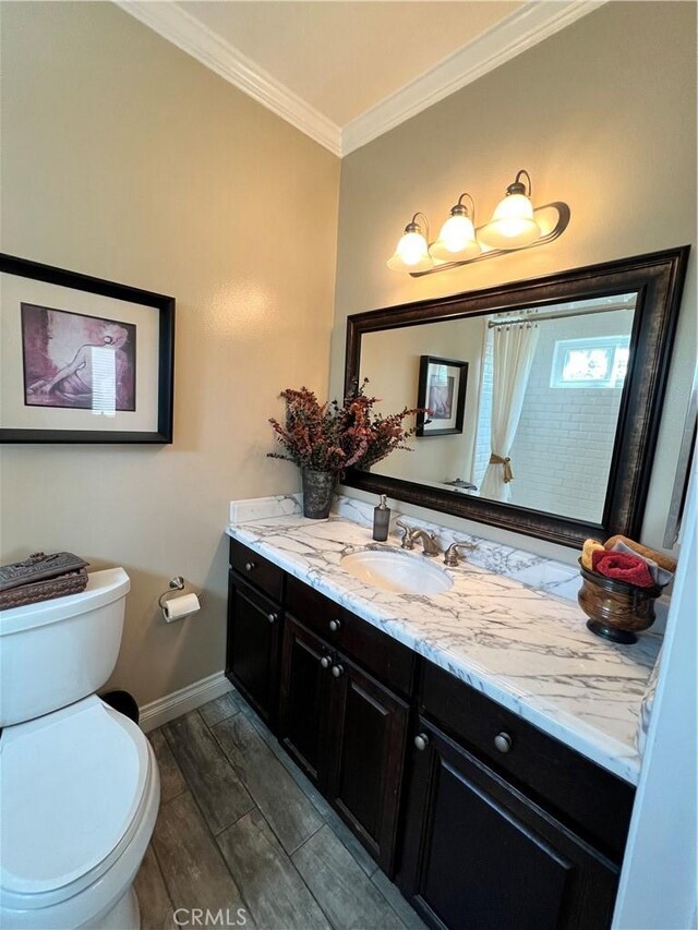 bathroom featuring toilet, vanity, and crown molding